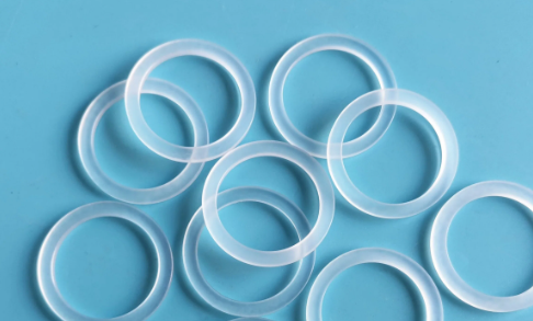 Transparente Silikonringe liegen überlappend verstreut auf einem hellblauen Hintergrund.